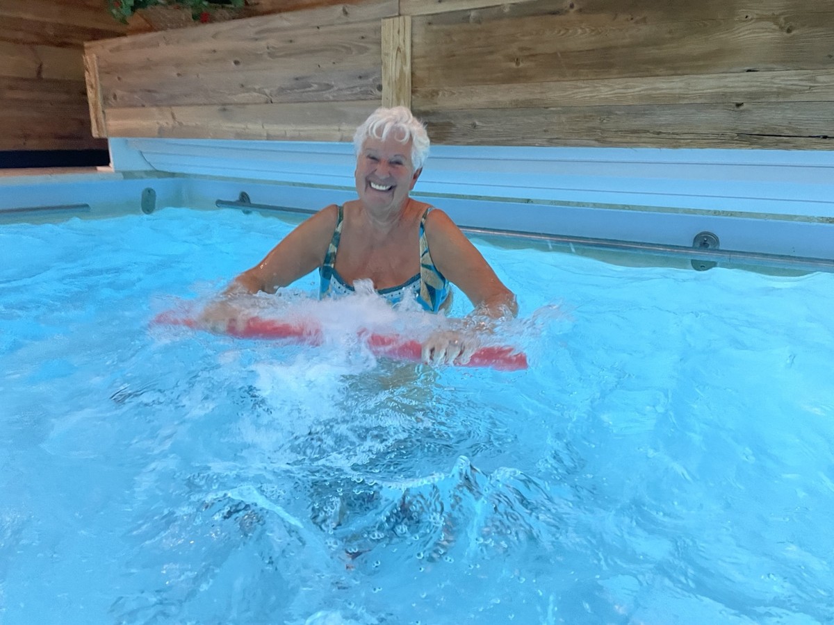 Lächelnde Teilnehmerin mit weißem Haar beim Aqua-Training